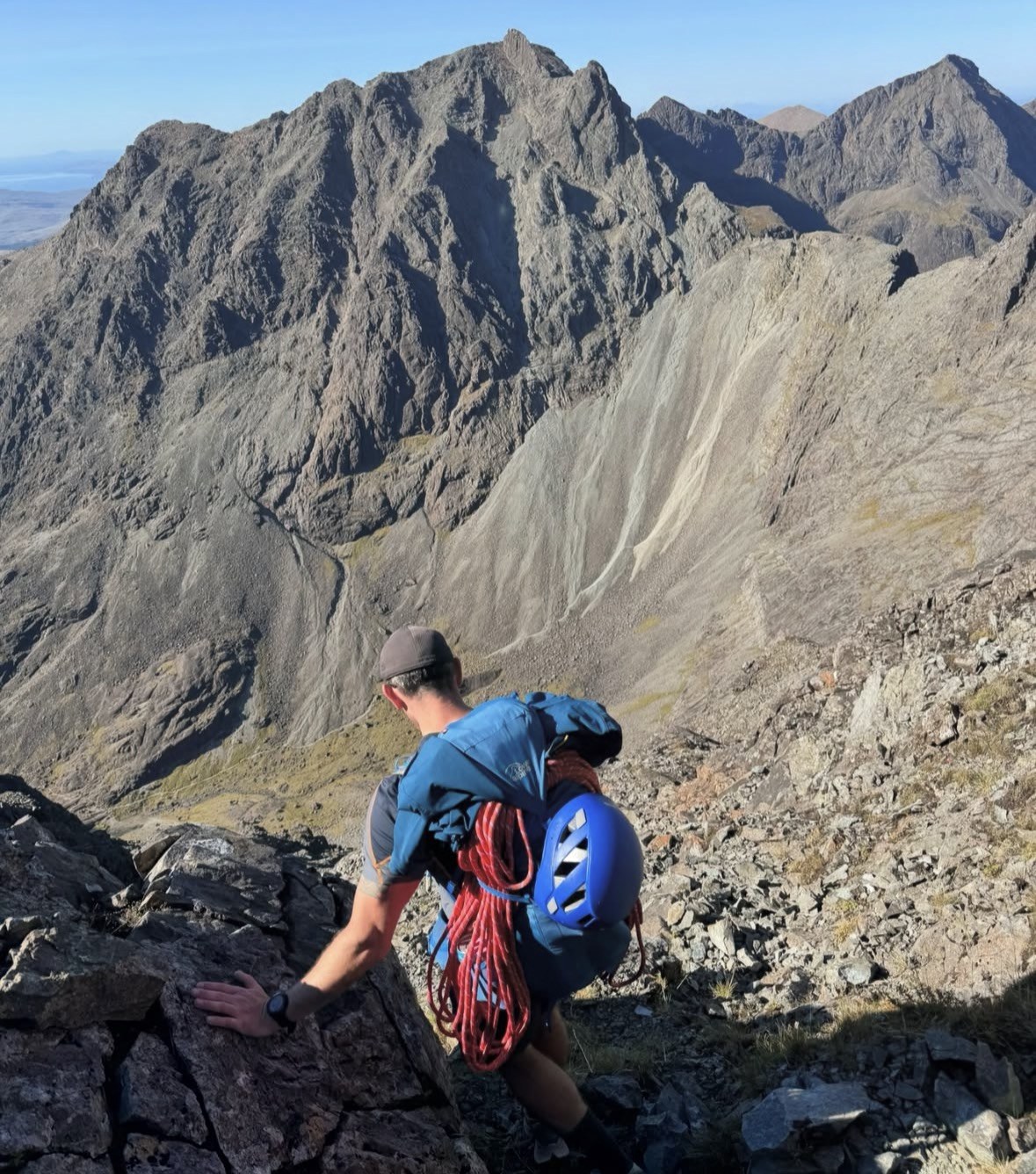 Alpinista con casco e corda in discesa sulla cresta rocciosa delle Black Cuillin