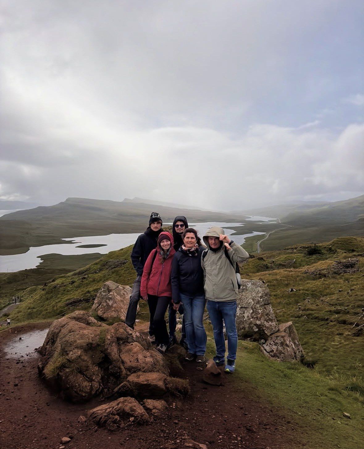 Famiglia di cinque in posa su un masso sopra i loch di Skye