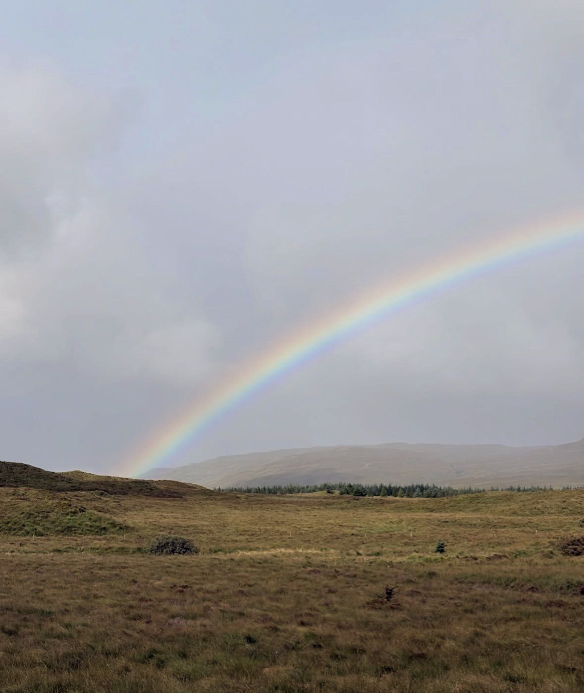 Arcobaleno sopra la brughiera aperta e le colline basse dell'Isola di Skye