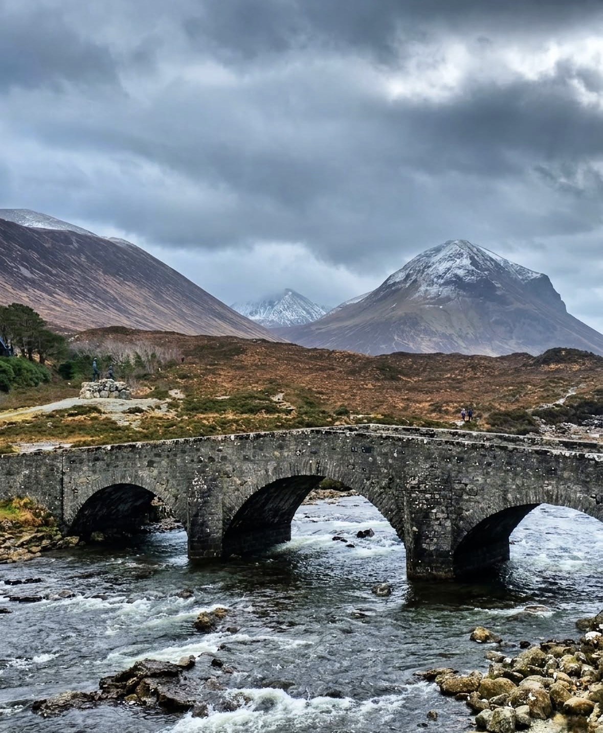 Archi del vecchio ponte di Sligachan sul fiume, Red Cuillin innevate dietro